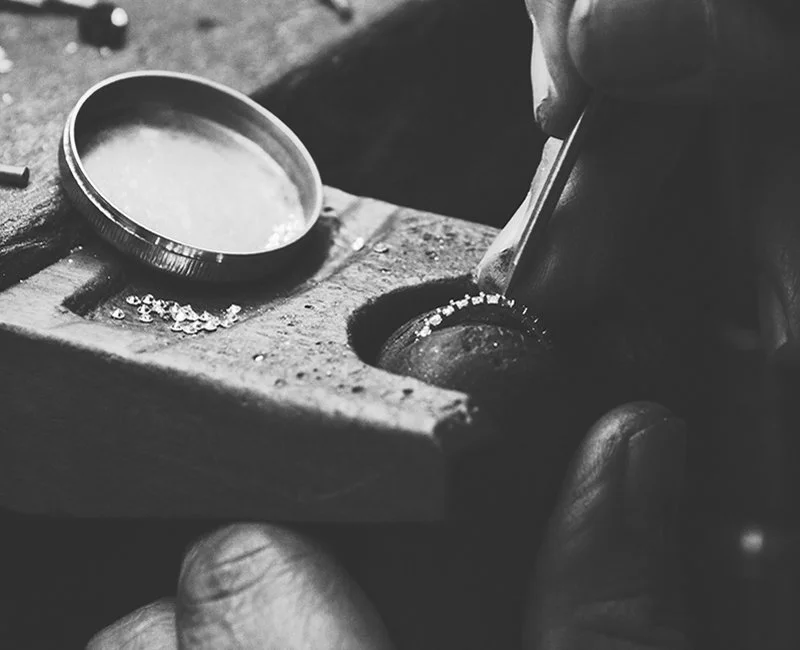 Jeweler hand-setting stones at the workbench